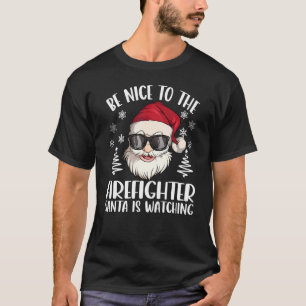 Camiseta Sé Agradable Con El Bombero Que Papá Noel Está Vie