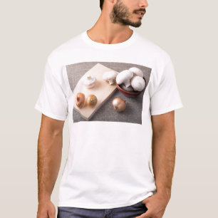 Camiseta Setas y cebollas crudas del champiñón en la tabl