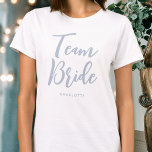 Camiseta Team Bride Boda Dusty Blue personalizado<br><div class="desc">¡Celebra tu brida con esta camiseta boda personalizada! Las palabras "Team Bride" se escriben en un tipo de letra de guión moderno y, a continuación, puede agregar un nombre personalizado, una fecha de boda, una ubicación u otro texto. ¡Un regalo encantador para una fiesta de soltera, una ducha de boda...</div>