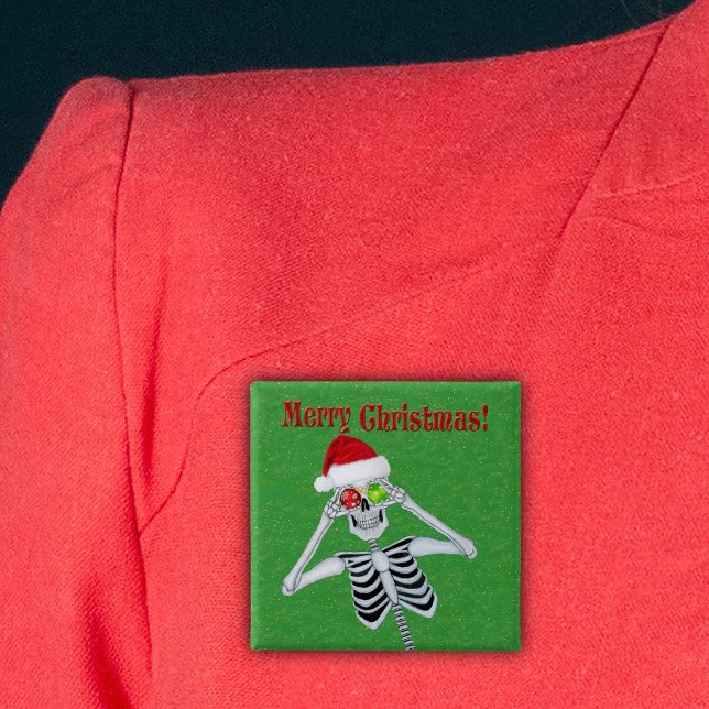 Chapa Cuadrada Feliz Navidad Feliz Skeleton Santa Hat Green (Happy Christmas skeleton holding ornaments in Santa Hat on green with gold flecks pin back button.)