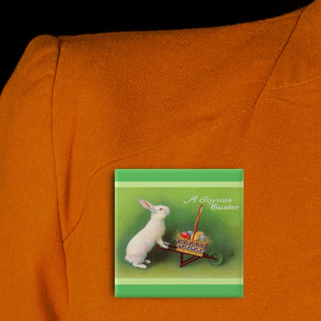 Chapa Cuadrada Huevos de cesta de conejo de Pascua (Joyous Easter white rabbit pushing wheelbarrow coloured eggs on green pin back button.)