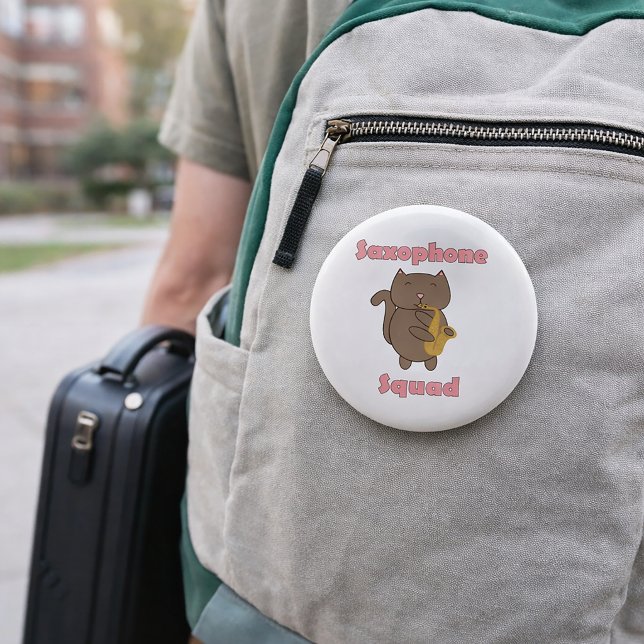 Chapa Redonda De 5 Cm Saxophone Squad Gatito Kawaii Rosa (A pin featuring a brown cat playing saxophone and the words saxophone squad in pink.)