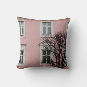 COJÍN DECORATIVO ÁRBOL DESCUBIERTO FRENTE A UN EDIFICIO DE COLOR RO
