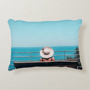Cojín Decorativo Mujer con gorra de paja blanca sentada en un banco