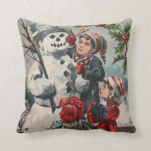 Cojín Decorativo Niños haciendo un muñeco de nieve con acebo