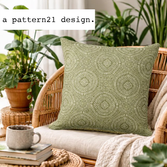 Cojín Decorativo patrón verde bohemio (Olive geometric accent pillow styled in a bright plant-filled living space.)