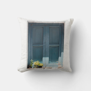 COJÍN DECORATIVO PUERTA DE MADERA AZUL EN MURO DE CONCRETO BLANCO