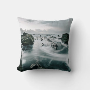 COJÍN DECORATIVO ROCA MARRÓN Y CUERPO DE AGUA RODEADO DE CLIFF