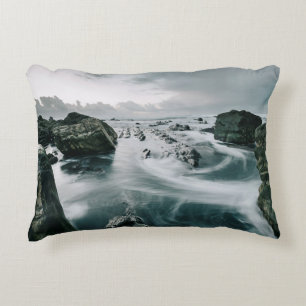 COJÍN DECORATIVO ROCA MARRÓN Y CUERPO DE AGUA RODEADO DE CLIFF