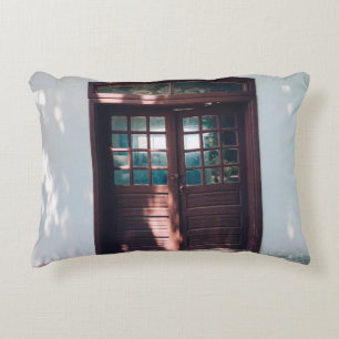 COJÍN DECORATIVO VENTANA DE MADERA MARRÓN EN MURO DE CONCRETO AZUL
