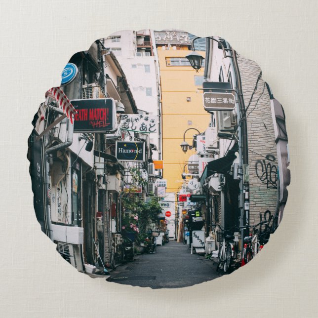 COJÍN REDONDO CALLE ENTRE EDIFICIOS DE CONCRETO GRIS (Anverso)