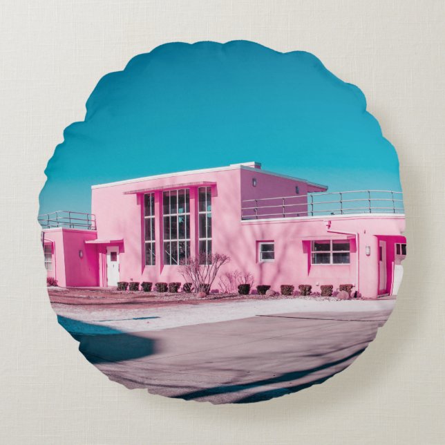 Cojín Redondo Edificio de hormigón rosa bajo un cielo azul claro (Anverso)