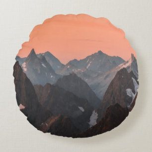 COJÍN REDONDO MONTAÑAS BLANCAS Y MARRÓN BAJO EL CIELO NARANJA