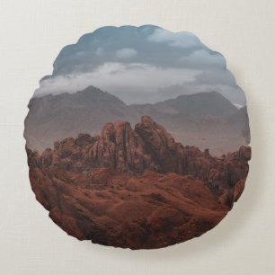 COJÍN REDONDO MONTAÑAS ROCAS BAJO CIELOS GRIS