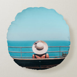 Cojín Redondo Mujer con gorra de paja blanca sentada en un banco