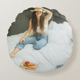 Cojín Redondo Mujer sentada en la cama sosteniendo a su gorra