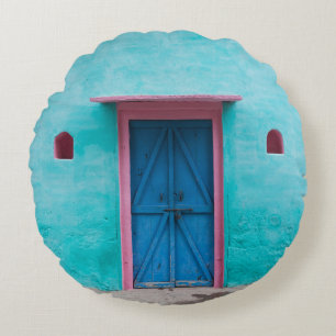 COJÍN REDONDO PUERTA DE MADERA ROJA EN PARED DE CONCRETO AZUL