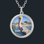 Collar Plateado Sun Day Ocean Beach Pier Pelican Bird Photo Cute<br><div class="desc">"Día del sol". Este adorable y feliz pelícano encaramado en una barandilla que da a una playa de California grita "listos para las vacaciones". Si viajas con este colorido collar de encanto fotográfico, regresarás a la cálida brisa oceánica. Este collar se presenta en pequeños, medianos y grandes tamaños, así como...</div>