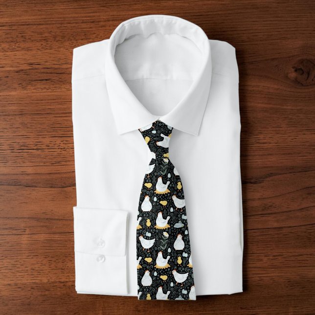 Corbata Papá Pollo de Traspatio Granjero Excéntrico Coloni (A black tie with a graphic chicken pattern design on it, atop a folded white collared shirt.)