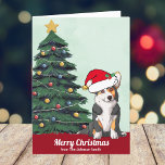 Corgi tricolor Navidad con Personalizado de cola<br><div class="desc">Este hermoso perro tricolor de Corgi galés Pembroke tiene la cabeza inclinada dentro de un lindo gorra de Santa Claus. El cachorro con cola está sentado frente a un árbol de Navidad bonito decorado con adornos coloridos. Feliz Navidad está escrito en el frente con una bonita cursiva en esta tarjeta...</div>
