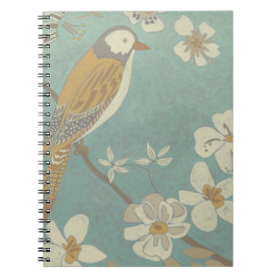 Cuaderno Ave amarilla, gris y beige colocada en una rama