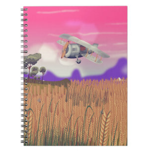 Cuaderno Avión biplano volando sobre cultivos bajo el sol p