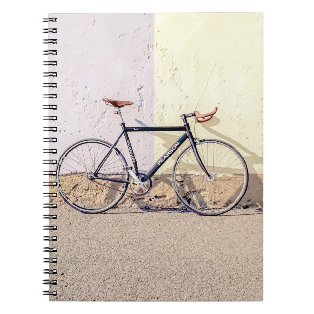 CUADERNO BICICLETA NEGRA Y GRIS EN MURO BLANCO (Frente)