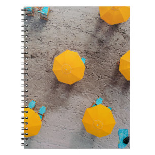 Cuaderno Cinco paraguas amarillos en la arena durante el dí
