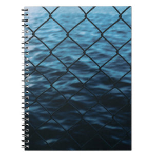 Cuaderno Cuerpo de agua delante de la cerca de eslabón de l