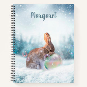 Cuaderno de conejo orando en la nieve