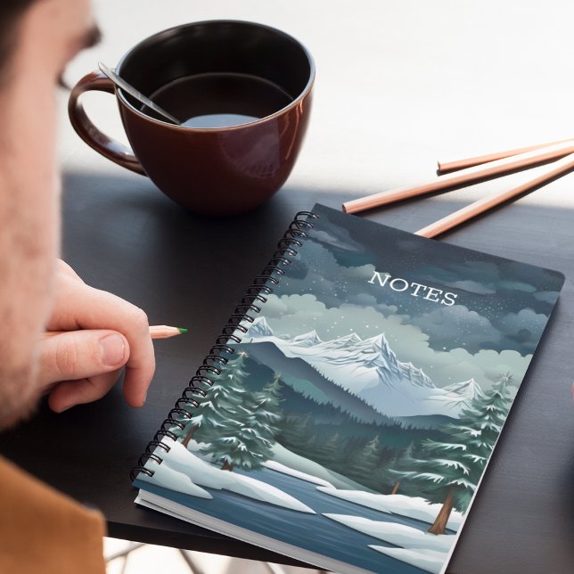 Cuaderno Escenario del bosque de invierno (A snowy forest mountain scene notebook on a desk with pencils and coffee.)