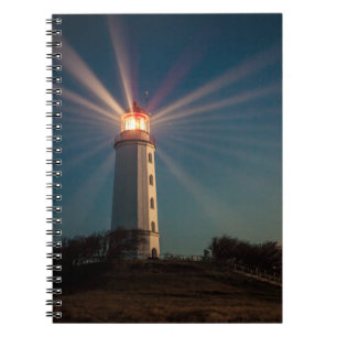 Cuaderno Faro en una colina que brilla por la noche