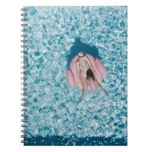 Cuaderno Mujer en boya rosa rodeada de un cuerpo de agua en
