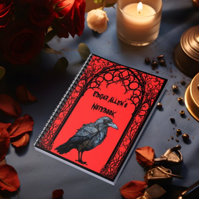 Cuaderno Raven gótico personalizado (A notebook with a raven and gothic frame on the cover lies on a table.)