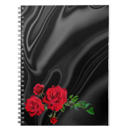 Cuaderno res rosas sobre un paño negro