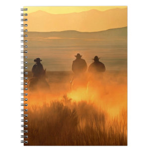 Cuaderno Tres vaqueros galopando sobre un fondo de montaña