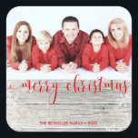 Cuadrada Rustic Wood Merry Christmas - Pegatina de fotos<br><div class="desc">Moderno ilustracion de moda Navidades de vacaciones con un fondo rústico de madera y un guión de tipografía roja "Feliz Navidad" en el texto y copos de nieve y bokeh decorativos. Cambiar fácilmente la foto de muestra con la suya.</div>