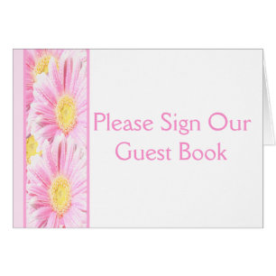 Daisies de Gerbera rosada en tarjeta de mesa blanc