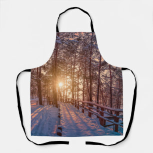 Delantal Atardecer en un bosque de pinos nevado con rayos s
