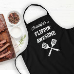 Delantal Flippin Awesome Personalizado Black Grilling<br><div class="desc">El delantal perfecto para el chef, cuyas habilidades espátulas son incomparables, ya sea dar vueltas a la parrilla o crepes a la plancha. Dos espátulas cruzadas aparecen en blanco bajo las palabras "Flippin' Awesome" en letras blancas con fondo negro. Añadir su nombre en guión retro. La manera perfecta de mostrar...</div>
