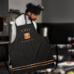 Delantal Monograma elegante chef de guiones de nombre dorad<br><div class="desc">Monogramado elegante y lujoso restaurante de cocina exclusiva,  el chef maestro delantal tiene una falsa plaza de purpurina metálico de cobre y líneas sobre un elegante fondo de cuero negro falso (IMPRESIÓN TEXTURE).          Personalízalo con título,  nombre e iniciales.</div>