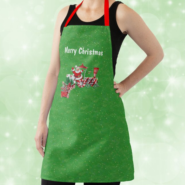 Delantal Navidades Tren Ruedas de Candy de Peppermint Santa (Santa on Merry Christmas Train with letters, candy canes on green with gold flecks kitchen apron.)