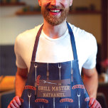 Delantal Nombre de la horquilla de parrillada de la Marina<br><div class="desc">Este diseño fresco y moderno es perfecto para el maestro de la parrillada. Se compone de una salchicha de color marrón, marrón, marrón, plateado, negro y dorado oscuro con un patrón de ilustracion de personalizado de tenedor asador sobre un patrón abstracto azul marino. Este diseño también incluye la frase "Grill...</div>