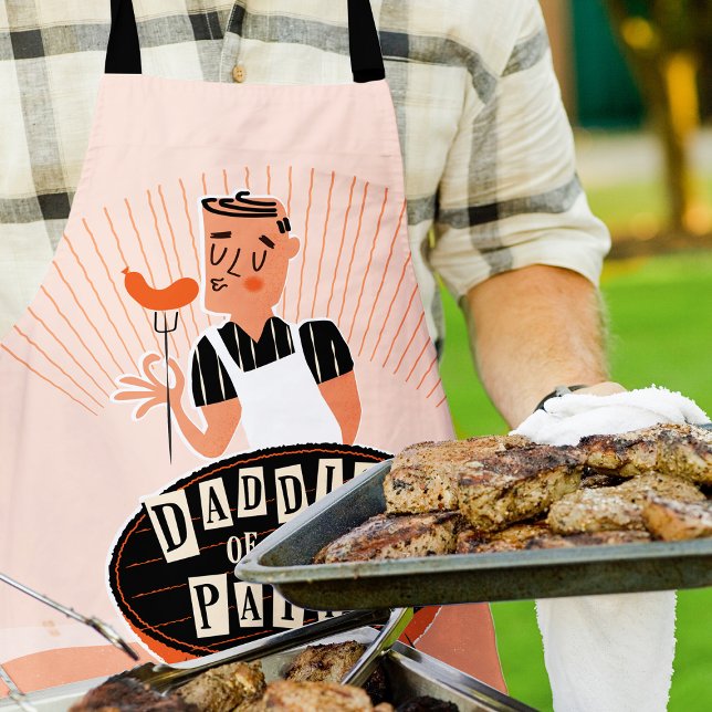Delantal Parrillada divertida para papá, Daddio de patio (Man outside wearing a "Daddio of the patio apron" while grilling and holding a large platter of meat)