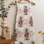 Delantal Vintage Nutcracker y Feliz Navidad<br><div class="desc">Un soldado Cascanero de estilo vintage bellamente ilustrado, resplandeciente en su atuendo clásico, se pone alto, sosteniendo un cartel de Feliz Navidad. Los ricos colores cálidos y los detalles intrincados evocan una sensación de yuletide nostalgia, lo que lo convierte en una elección perfecta para aquellos que aprecian la estética clásica...</div>