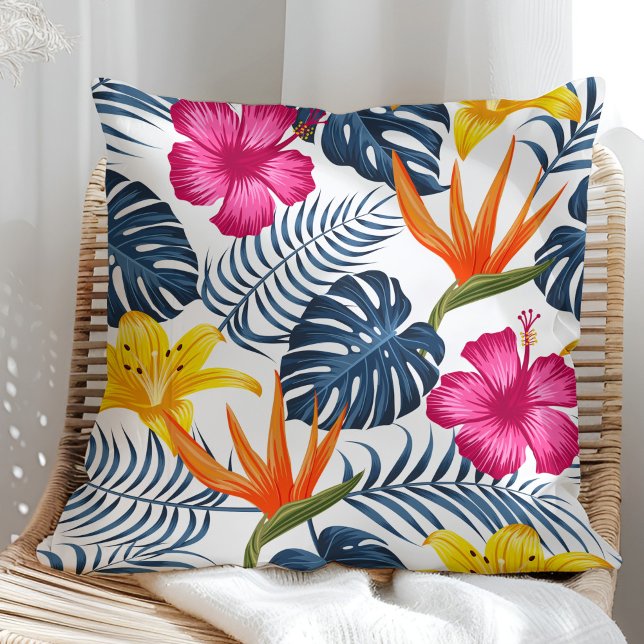 Diseño tropical colorido sobre una almohada blanca (Colorful tropical design on a white pillow in a sunny rattan armchair.)