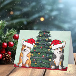 Dos Corgi Árbol de Navidad Perro Santa Sombrero<br><div class="desc">Estos hermosos perros Pembroke Welsh Corgi tienen la cabeza inclinada dentro de un lindo gorra de Santa Claus. Las dos crías están sentadas frente a un árbol de Navidad bonito decorado con adornos coloridos. Bonita tarjeta de vacaciones de corgis con un maravilloso dibujo de tricolor y un par de corgi...</div>