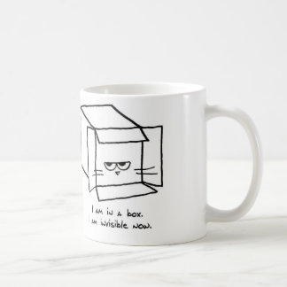 El gato enojado oculta en una caja - taza de café