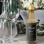 Elegante Boda negro simple Gracias Mini<br><div class="desc">Las etiquetas de estas botellas de mini vino presentan un diseño sencillo pero elegante, con una caligrafía lacada en blanco sobre un fondo negro con un borde enmarcado. Adición perfecta a un bolso de boda, o como favores para los invitados, la familia y los miembros de su fiesta nupcial. El...</div>