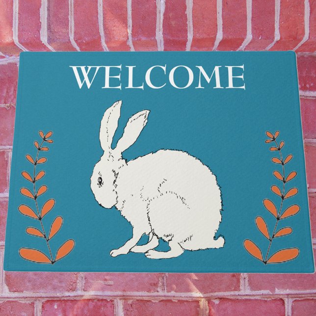 Felpudo Elegante sentando plantas de Naranja de conejo bla (White sitting rabbit with tall orange plants on dark blue Welcome outdoor mat.)